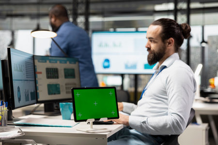 Corporate expert uses pc monitor to analyze charts with a mockup on tablet, preparing strategy...