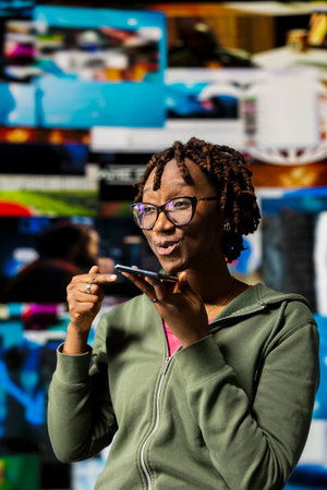 Smiling woman records voice note on smartphone, thrilled to talk about movie with friend, videowall...