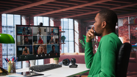 African american guy at desk is engaged in video call with coworkers, speaking about latest business...