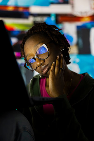 Close up of young woman addicted to watching internet clips, unable to stop using notebook. Lazy teenager staring at laptop display, concept of technology overuse and digital dependenceの写真素材