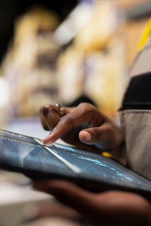 Close up of black employee verifying airway bill tags on the racks, fulfillment center operations within an industrial warehouse. Shipment and inventory management for large business.の写真素材