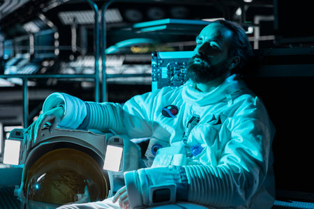 Spaceman lying on shuttle floor, losing hope after space station catastrophe. Blue lights flashing over man facing medical crisis triggered by extreme cold in spaceship with broken hullの写真素材