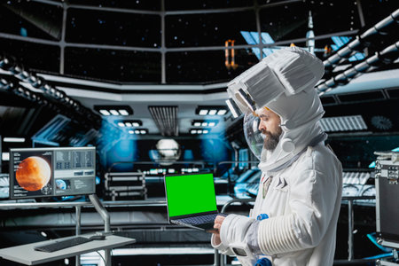 Astronaut checks isolated screen laptop interface before landing spaceship on Mars. Crew member looking at mockup notebook during mission to red planet surface, testing human survival in deep spaceの写真素材