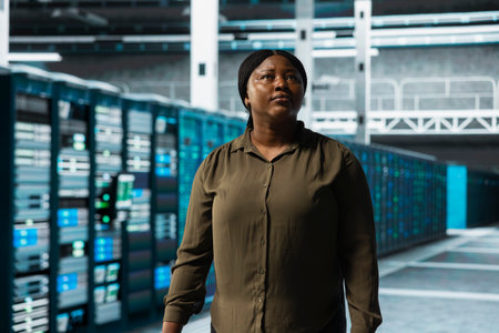 Engineer walking through server farm rows lined with storage infrastructure rigs. IT expert...