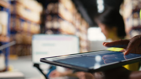 Close up of african american person checking tracking info for parcels on tablet, ensuring correct...