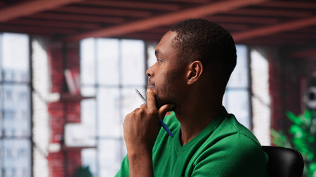 Young remote worker being pensive thinking about new ideas to make money, using his creativity and...