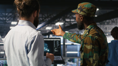 Military units overseeing AI computing operations on notebook in high tech server facility. Army tech experts using machine learning intelligence to oversee communication systemsの写真素材