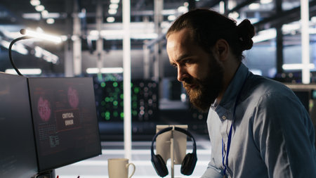 Engineer in data center frustrated by critical error popup on monitor during diagnostics session. IT expert stressed while troubleshooting system fault affecting infrastructure performance, camera Aの写真素材