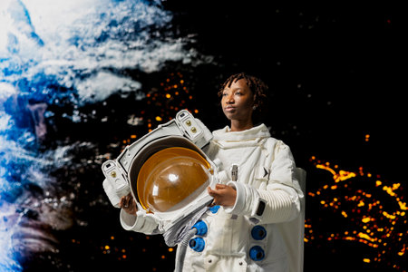 Woman holding astronaut helmet cosmonaut looking at planet, mentally preparing for landing. African american woman astronaut doing Martian surface research, researching planet habitatsの写真素材