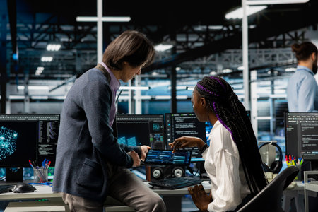 Team leader helping intern in data center to use AI LLM assistant to do maintenance on rigs. Manager and trainee doing internship in server hub, using large language model chatbot to do backupsの写真素材