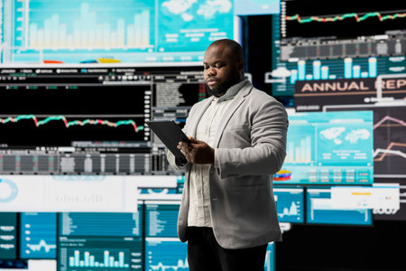 Young businessman thinking about a new solution to increase funds, evaluating statistics and financial reports with digital technology and analytics. Long term success and growth.の写真素材