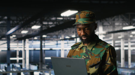 Army IT specialist in data center using laptop to defend networks against cyber threats. Military command center admin using notebook to identify potential intrusions or malicious activitiesの写真素材