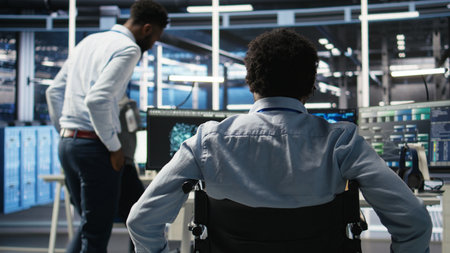 Data center programmer in wheelchair entering office uses AI node tree program to minimize system downtime. Server room IT expert in disability uses machine learning visual programming tool, camera Aの写真素材