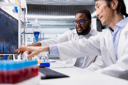 Team of biochemists in laboratory pointing to computer display, doing DNA data analysis. Research...