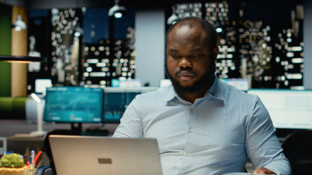 Male company analyst reading data reports and fact checking on laptop, planning project and...