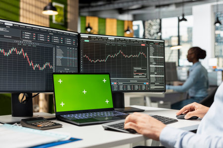 Risk analyst monitors live market activity on isolated screen laptop to identify market volatility...