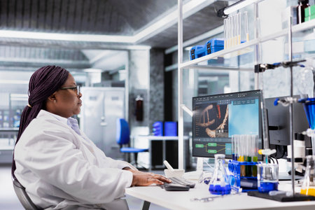 Black woman working in biotechnology lab surrounded by modern equipment. Conducting research study for genetics, nanotechnology and healthcare data, supporting pharmaceutical science.の写真素材