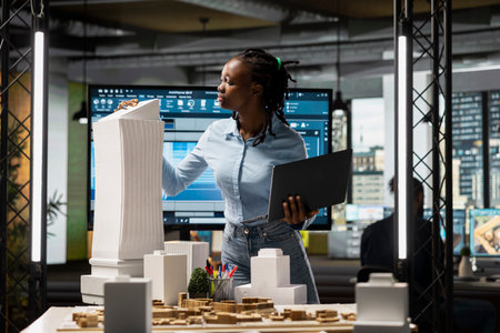 Black female developer reviewing zoning regulations with 3D models, residential project with a...