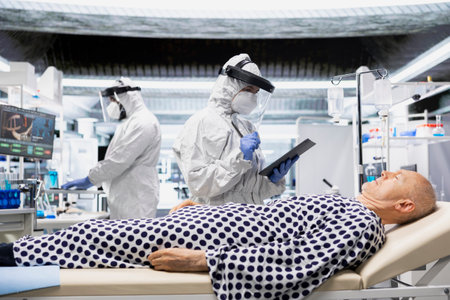 Scientist in protective gear conducting evaluation on patient with viral symptoms, gathering data to develop a new drug for medical progress. Global pandemic response and safety.の写真素材