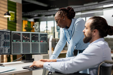 Risk analyst and coworker with disability in inclusive office using trading platform to review stock...