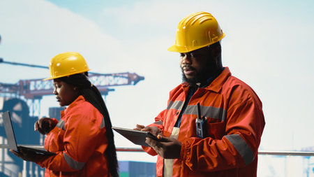 Drilling rig engineering team using tablet and laptop to evaluate ocean contamination prevention...