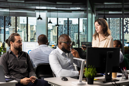 Diverse employees exchanging insights and new ideas to meet objectives, doing report sharing and forecasting at pc desk in the office. Work team managing business intel for development.の写真素材