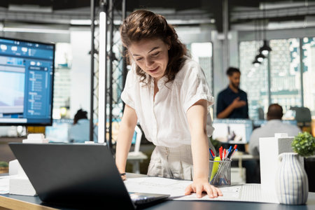 Woman real estate professional evaluating city housing blueprints in the office, studying architectural layout plans and zoning regulations for project approval. Infrastructure growth.の写真素材