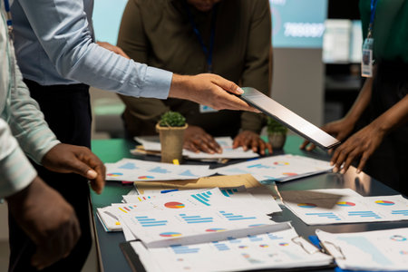 Close up of business people prepare for a pitch by reviewing financial data on documents inside the...