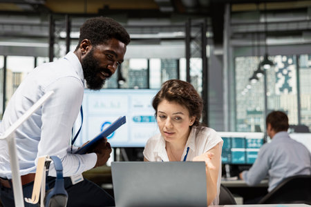 African american business manager collaborating with female assistant on project development, using online marketing strategies. Black man and white woman teamworking to improve company growth.の写真素材