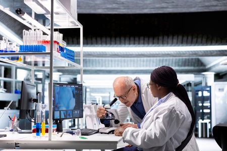Two researchers conducting microscopy experiment in modern laboratory. Observation of specimen tray...