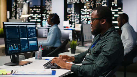 Office worker reviewing KPI metrics on monitor and analytics on desktop, building a vision and business strategy to accomplish objectives and success. Professional mindset after hours.の写真素材