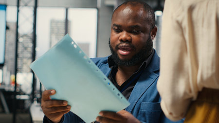 Close up of office secretary pushes a trolley filled with paperwork and documents, bringing files to a colleague and ensuring efficient distribution of resources. Workplace support. Camera B.の写真素材
