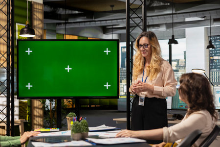 Corporate women gathering next to chroma key screen in modern office work environment, evaluating financial data, strategic indicators and other information during boardroom meeting.の写真素材