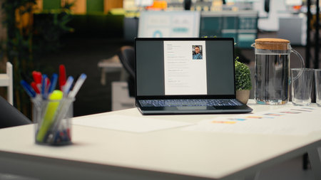 Laptop in empty corporate space shows applicant CV before hiring interview, office used for the recruitment process and reviewing qualifications or work experience to align with position.の写真素材