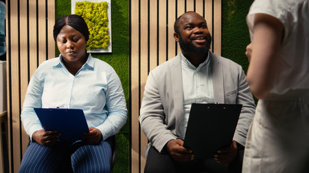 Black young man applicant getting called in for interview at HR office, sitting in the hallway and reviewing experience presentation on CV. Preparing for the hiring discussion. Camera A.の写真素材