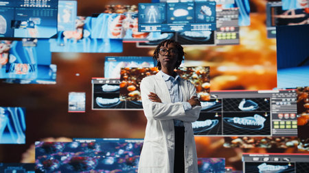 Clinician with arms crossed looking at medical reports on multimedia wall. Doctor wearing lab coat analyses medical research data, monitoring interactive dashboards, camera Aの写真素材