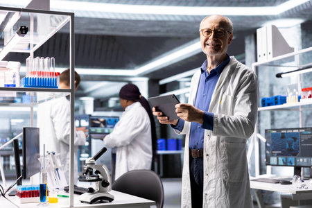 Male researcher focuses on experiment data in a research study. Laboratory equipment and chemical testing highlight biochemistry, genetics and bioengineering. Scientist work.の写真素材