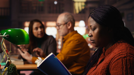 Colleagues reading in the library, african american pupil making a noise complaint and being disturbed by the disrespect.の写真素材