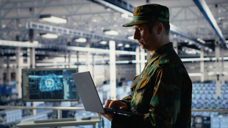 Army soldier in server farm uses artificial intelligence program on laptop to review reconnaissance information. Military data center worker uses deep learning to plan mission, camera Bの写真素材