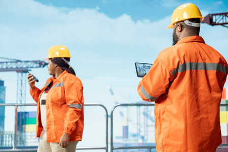 Offshore platform expert tracking oil production efficiency using tablet app. Drilling rig coworkers use device program to check equipment sensor readings, doing maintenanceの写真素材