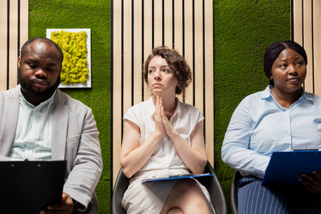 Confident job applicants sitting in the hallway before hiring interview, reviewing their CVs and preparing for employment questions with HR recruiters during a talent acquisition meeting.の写真素材