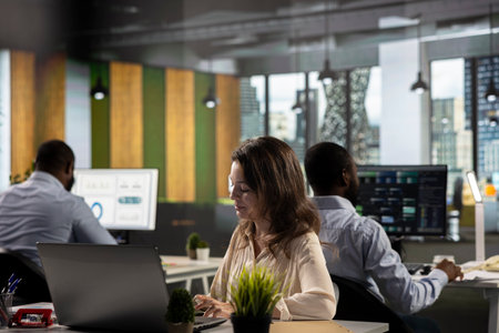 Business people gathered around laptops working on project tasks and targets for development. Office...