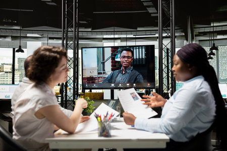 Black young applicant chatting with recruiting team during remote interview via video conference, exploring experience and qualifications to ensure alignment with position requirements.の写真素材