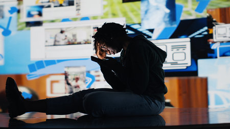 Teenager procrastinating on internet, using social media app on phone instead of doing school assignments. Lazy student using smartphone instead of doing homework, being unproductive, camera Bの写真素材