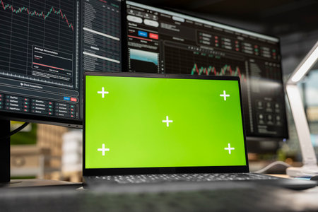 Close up of isolated screen laptop in brokerage office next to workstation monitor displaying live stock charts. Chroma key notebook device and PC with financial software in prop firm workspaceの写真素材