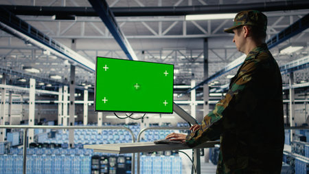 Military data center professional using software on green screen mockup PC to detect enemy threats. Army man in data center uses chroma key computer to detect issues , camera Aの写真素材