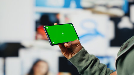 Isolated screen mobile phone used by person to look at internet video channels, isolated over digital backdrop. Woman enjoying metaverse video content using chroma key smartphone, camera Bの写真素材