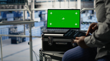 Close up of data center employees check AI dashboard using green screen tablet during systems review. Server hub workers test artificial intelligence tools on mockup device for reliable performanceの写真素材