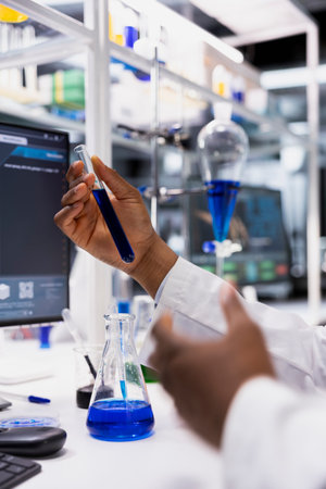 Close up of cytotechnologist using laboratory glassware filled with blue indicator solution in...