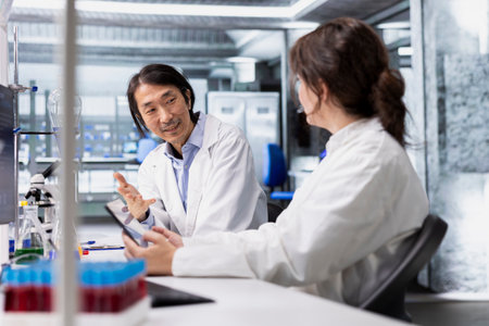 Coworkers talking, doing genetics study using clinical equipment in medical lab. Team of biotechnologists doing brainstorming, using scientific gear in research facility, doing complex experimentsの写真素材